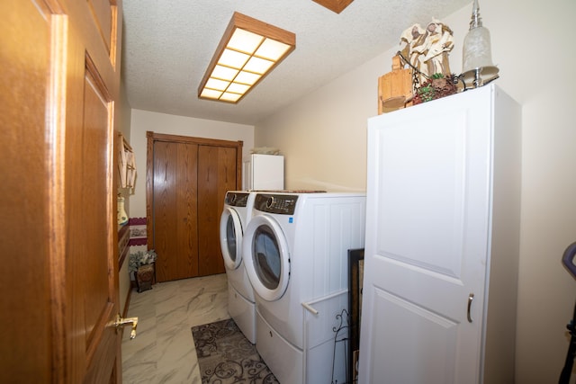 clothes washing area with independent washer and dryer and a textured ceiling