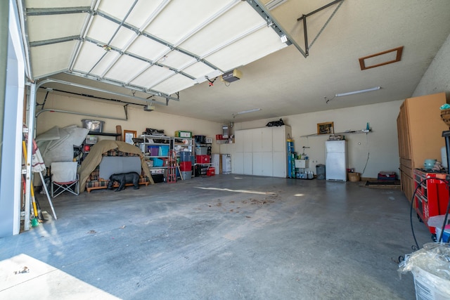 garage featuring white refrigerator and a garage door opener