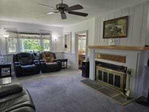 carpeted living room with ceiling fan and a tiled fireplace