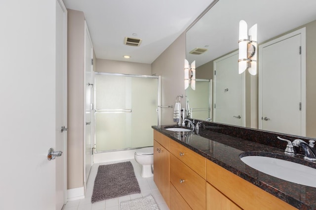 bathroom with tile patterned floors, vanity, a shower with shower door, and toilet