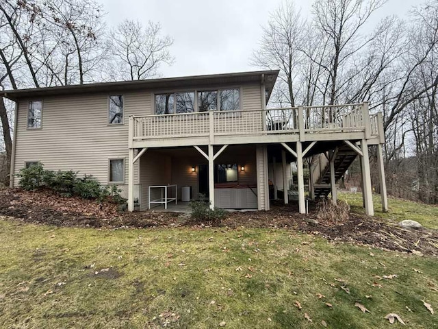 rear view of property featuring a lawn, a deck, a patio, and a hot tub