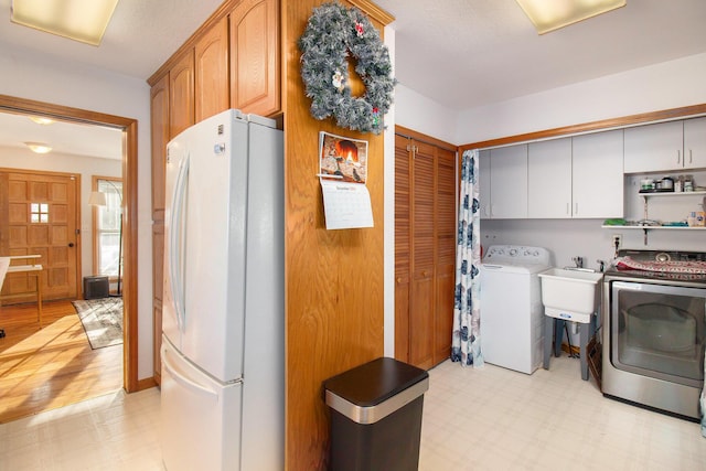 washroom with cabinets, sink, light hardwood / wood-style floors, and washing machine and clothes dryer