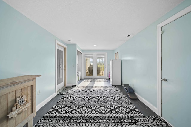 corridor with french doors and a textured ceiling