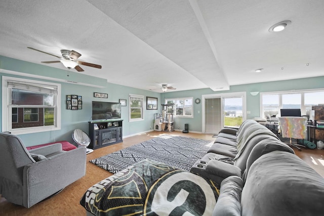 living room with ceiling fan, light hardwood / wood-style flooring, and a textured ceiling