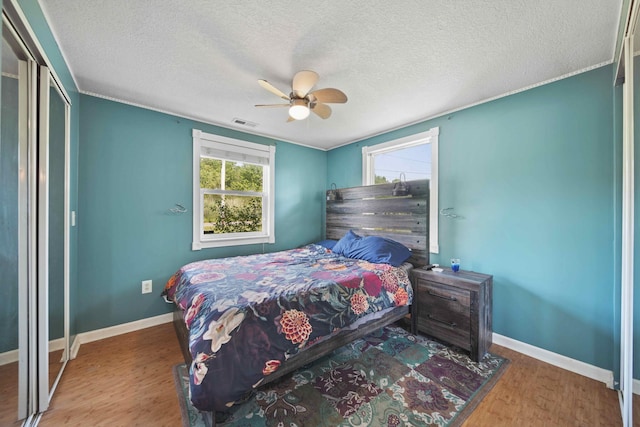 bedroom featuring ceiling fan, wood-type flooring, and a textured ceiling