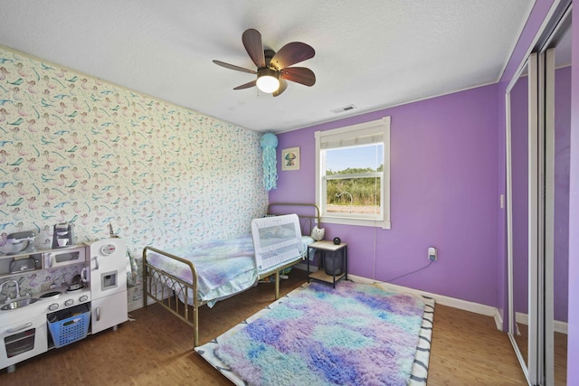 bedroom featuring ceiling fan, hardwood / wood-style floors, and a textured ceiling