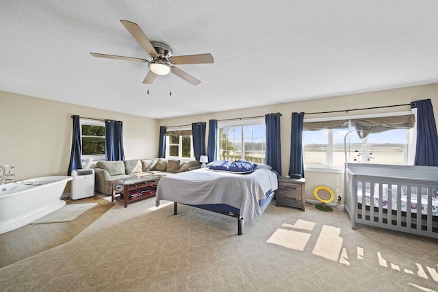 bedroom with a textured ceiling, ceiling fan, and light carpet