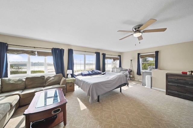 bedroom featuring ceiling fan, light carpet, and a textured ceiling