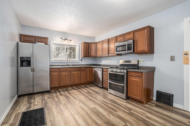 kitchen with a textured ceiling, dark hardwood / wood-style flooring, sink, and stainless steel appliances