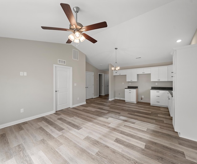 kitchen featuring white cabinets, ceiling fan with notable chandelier, light hardwood / wood-style floors, and vaulted ceiling