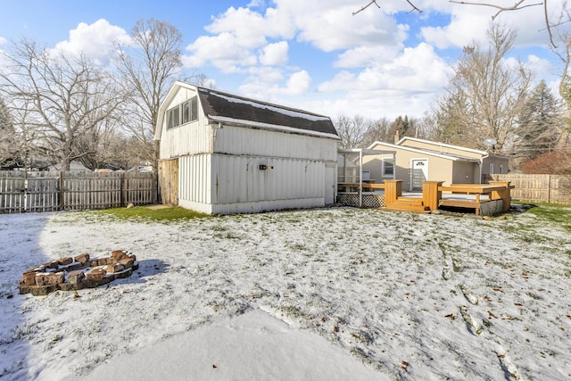 yard layered in snow featuring a shed and a wooden deck