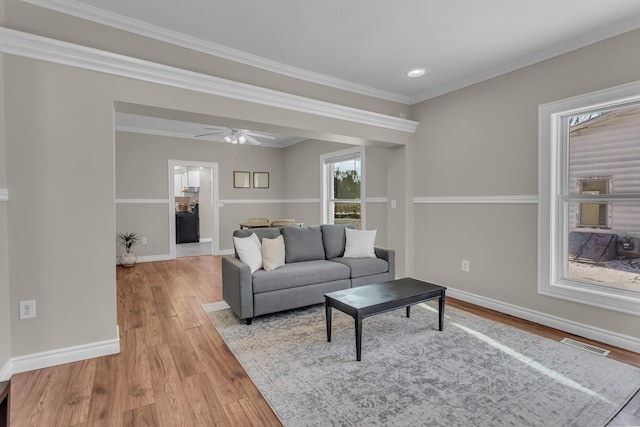 living room with light wood-type flooring, ceiling fan, and crown molding