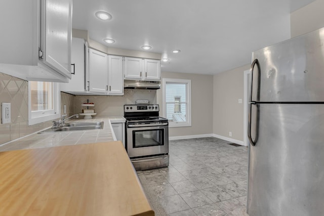 kitchen featuring backsplash, stainless steel appliances, white cabinetry, and sink