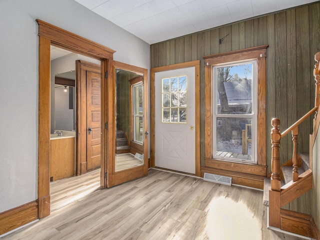 doorway featuring light hardwood / wood-style floors and wooden walls