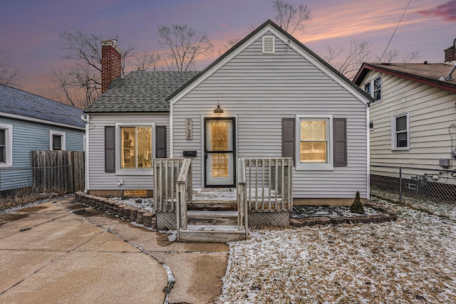 view of front of home with roof with shingles, fence, and a chimney