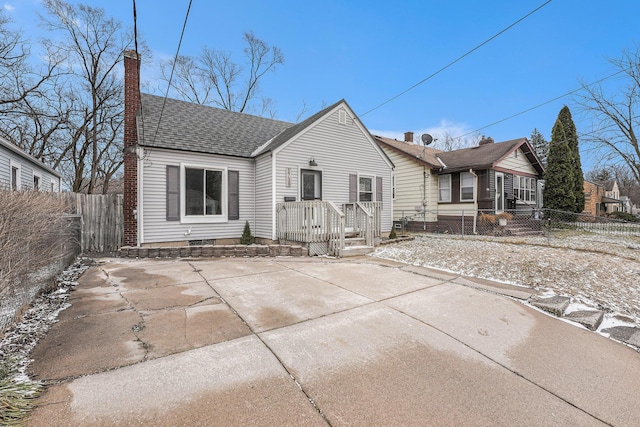 rear view of house with a shingled roof, a chimney, and fence