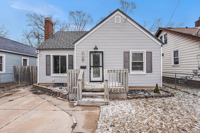 view of front of house with roof with shingles, fence, and a chimney