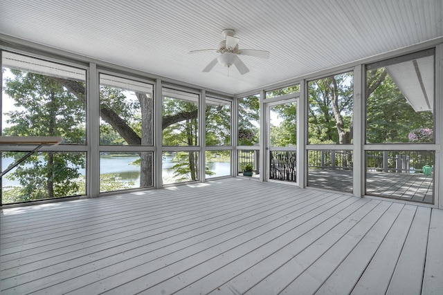 unfurnished sunroom with ceiling fan and a water view