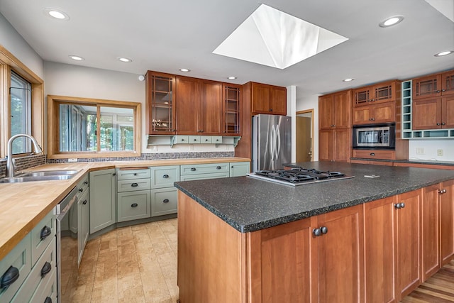 kitchen featuring sink, a skylight, light hardwood / wood-style floors, a kitchen island, and stainless steel appliances