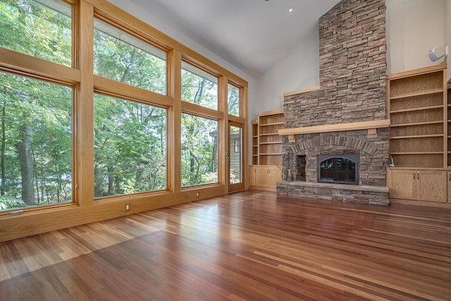 unfurnished living room with hardwood / wood-style flooring, a healthy amount of sunlight, a fireplace, and high vaulted ceiling