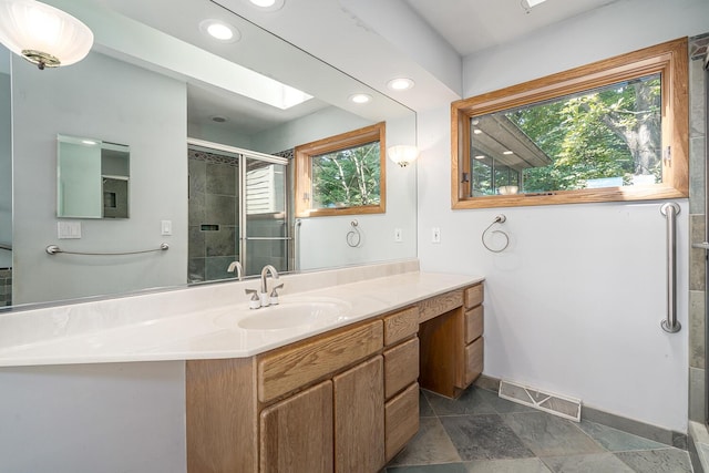 bathroom with an enclosed shower, vanity, a skylight, and a wealth of natural light