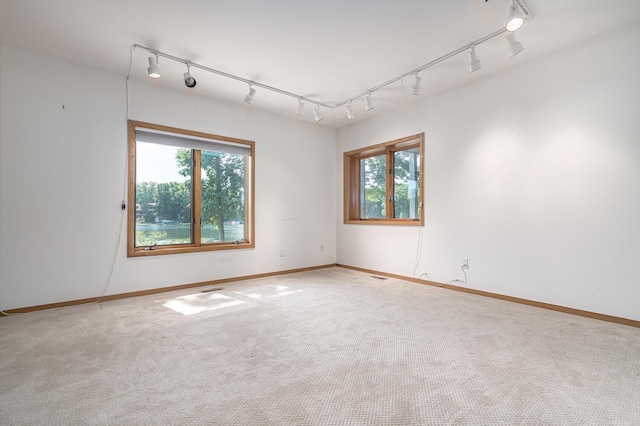 carpeted spare room featuring rail lighting