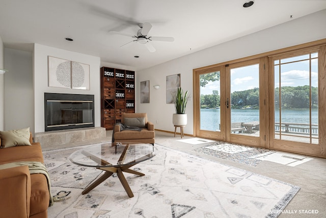 living room featuring ceiling fan, french doors, a water view, and a healthy amount of sunlight