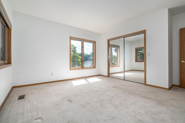 unfurnished bedroom featuring light carpet and a closet