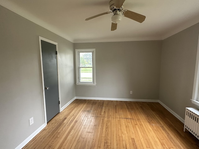 spare room featuring ceiling fan, radiator, and light hardwood / wood-style flooring