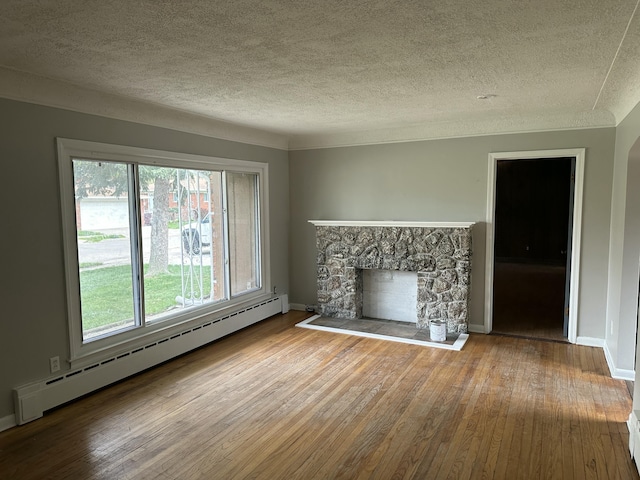 unfurnished living room featuring hardwood / wood-style floors, a fireplace, baseboard heating, and a textured ceiling