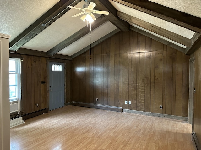 interior space with light wood-type flooring, a textured ceiling, ceiling fan, a baseboard radiator, and wood walls