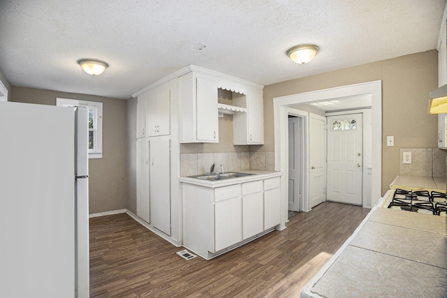 kitchen with white fridge, sink, white cabinetry, and dark wood-type flooring