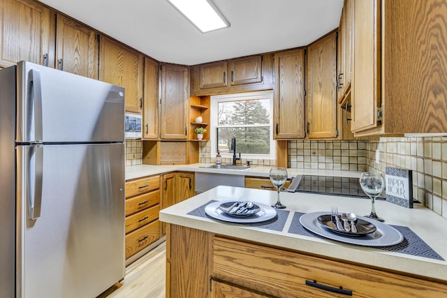 kitchen featuring backsplash, stainless steel fridge, sink, and light hardwood / wood-style floors