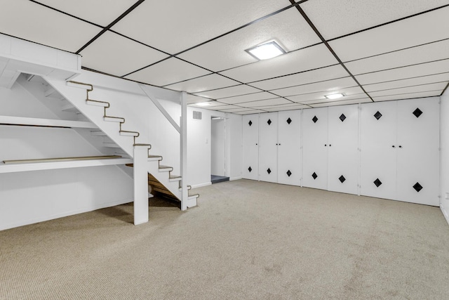 basement featuring a paneled ceiling and light colored carpet