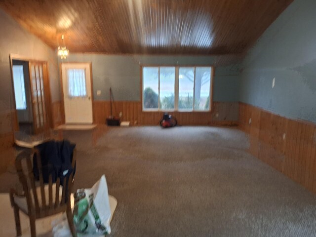 interior space featuring a notable chandelier, wood walls, and carpet floors