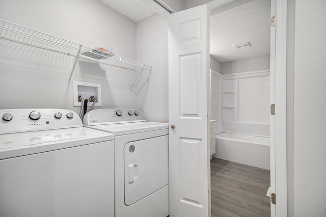 washroom with hardwood / wood-style floors, washer and dryer, and a textured ceiling