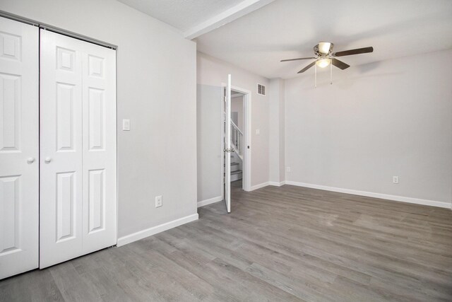 unfurnished bedroom with hardwood / wood-style flooring, ceiling fan, and a closet