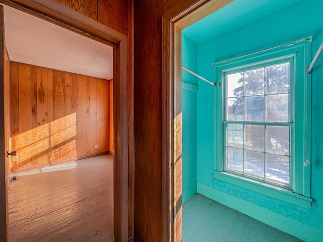 hallway with hardwood / wood-style flooring and wood walls