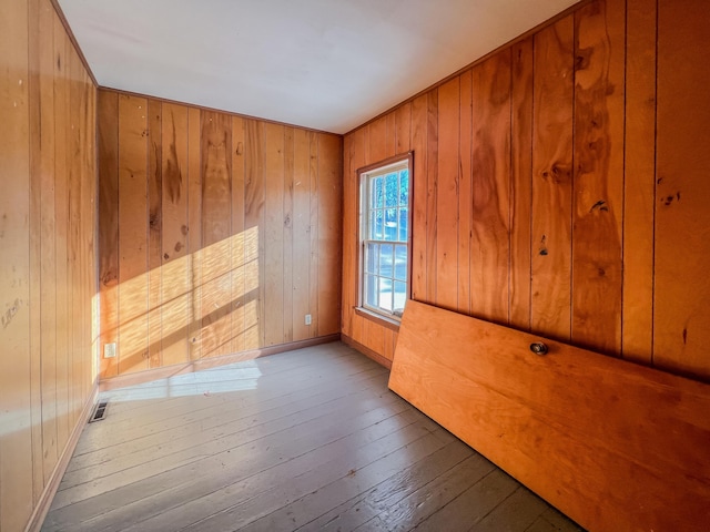 empty room featuring hardwood / wood-style flooring and wooden walls