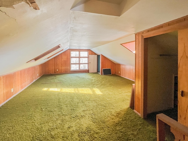 bonus room with carpet flooring, vaulted ceiling, and wooden walls