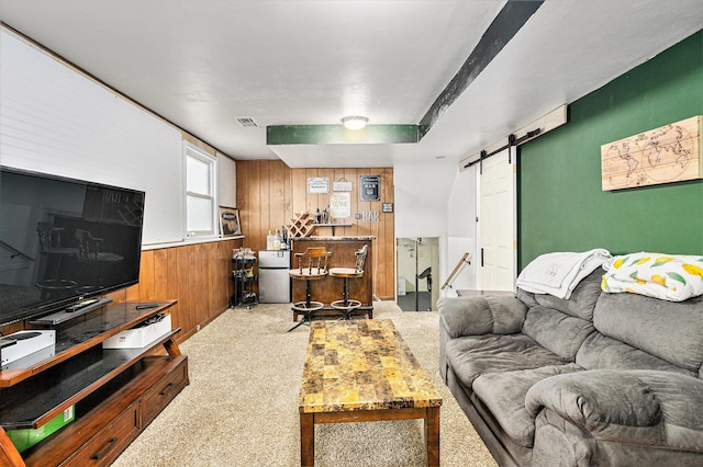 living room featuring a barn door, carpet floors, and wood walls