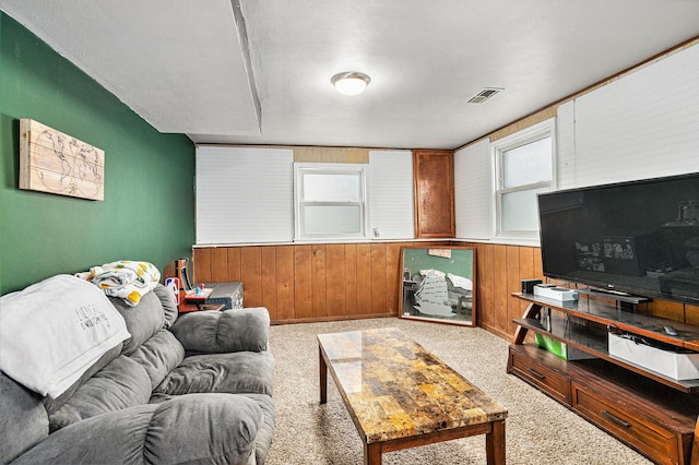 carpeted living room featuring wood walls