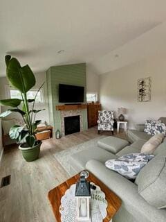 living room with wood-type flooring, a large fireplace, and lofted ceiling