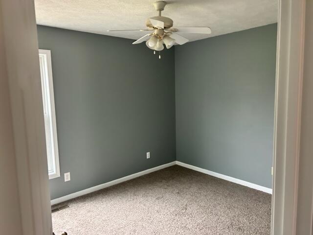 carpeted spare room with a textured ceiling and ceiling fan