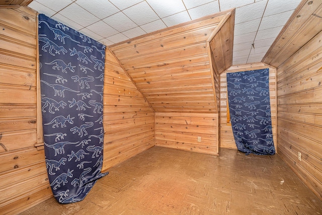 bonus room with wood walls and vaulted ceiling