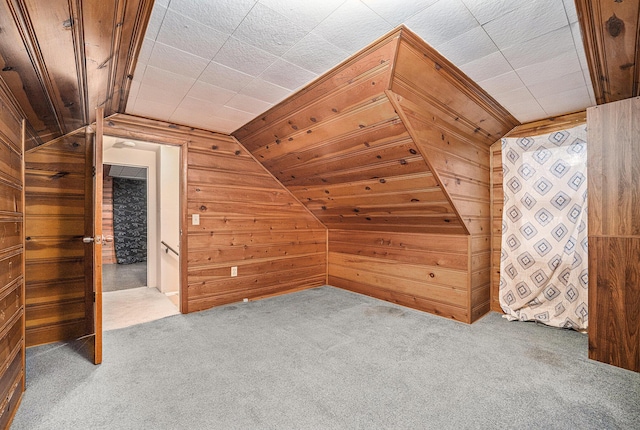 bonus room featuring carpet floors, wooden walls, and vaulted ceiling