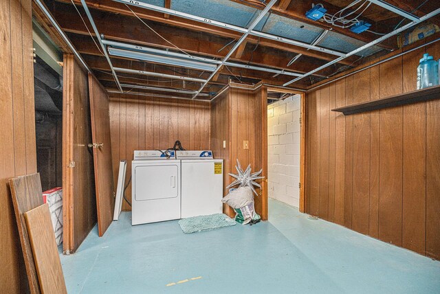 basement featuring washing machine and clothes dryer and wooden walls