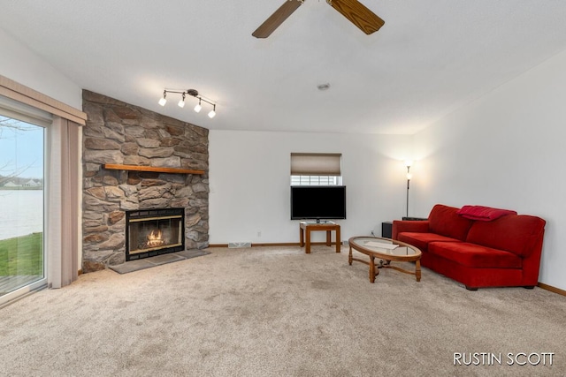 living room featuring ceiling fan, a water view, carpet floors, and a fireplace