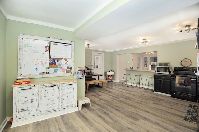 kitchen with hardwood / wood-style floors, black / electric stove, and ornamental molding