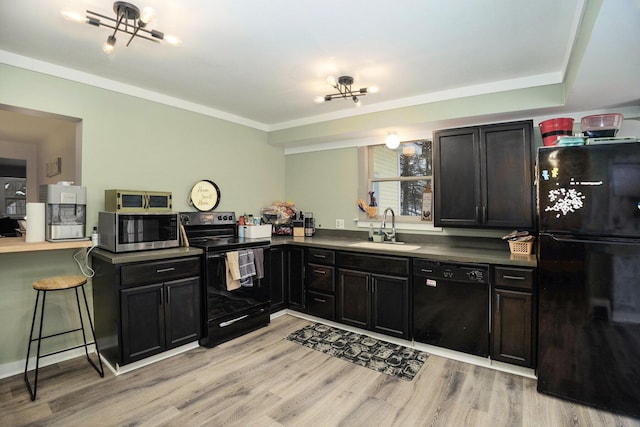 kitchen featuring sink, a kitchen breakfast bar, light hardwood / wood-style floors, black appliances, and ornamental molding